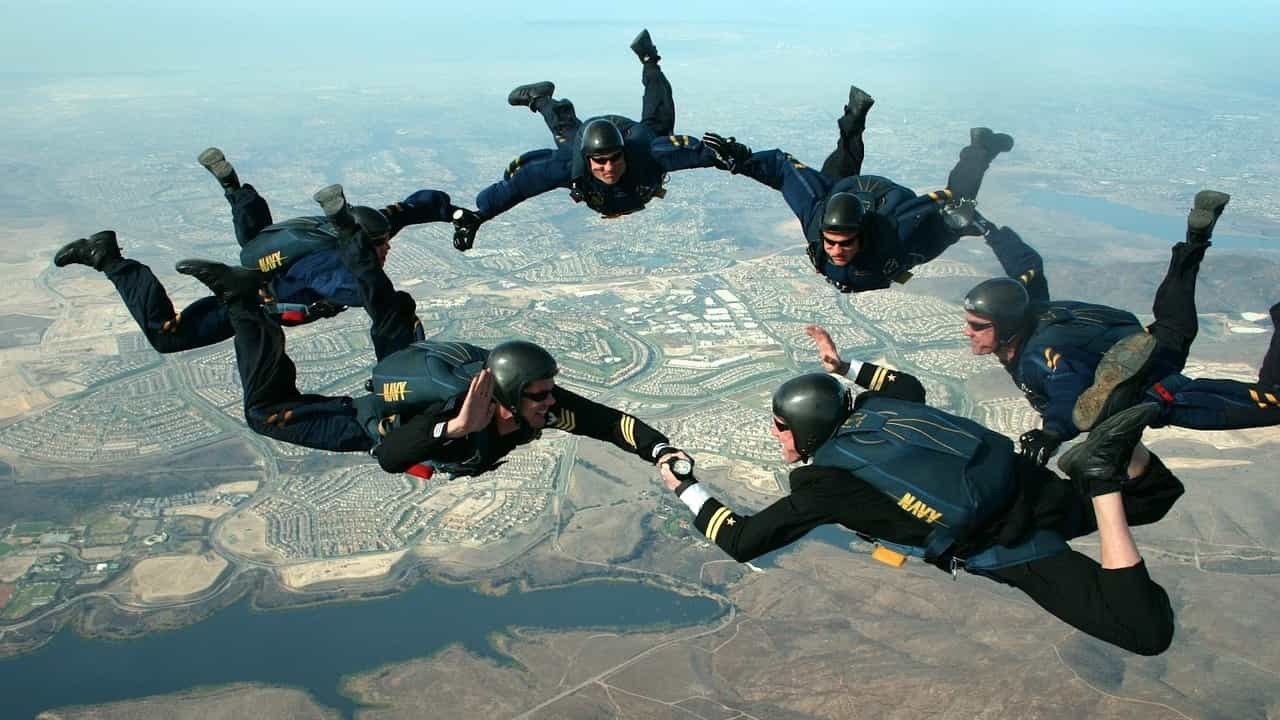 Group skydiving to illustrate the supportive nature between personal profiles and promoting a LinkedIn page.