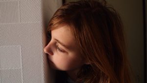 Woman peeking around a corner to illustrate "spying."