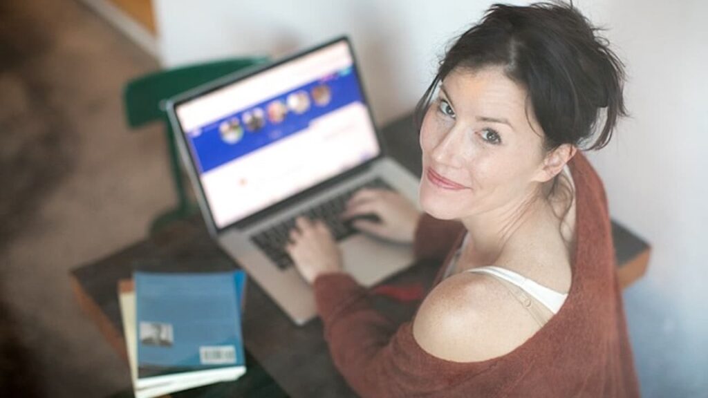 Image of a happy woman on her computer to illustrate how to come up with blog post ideas.